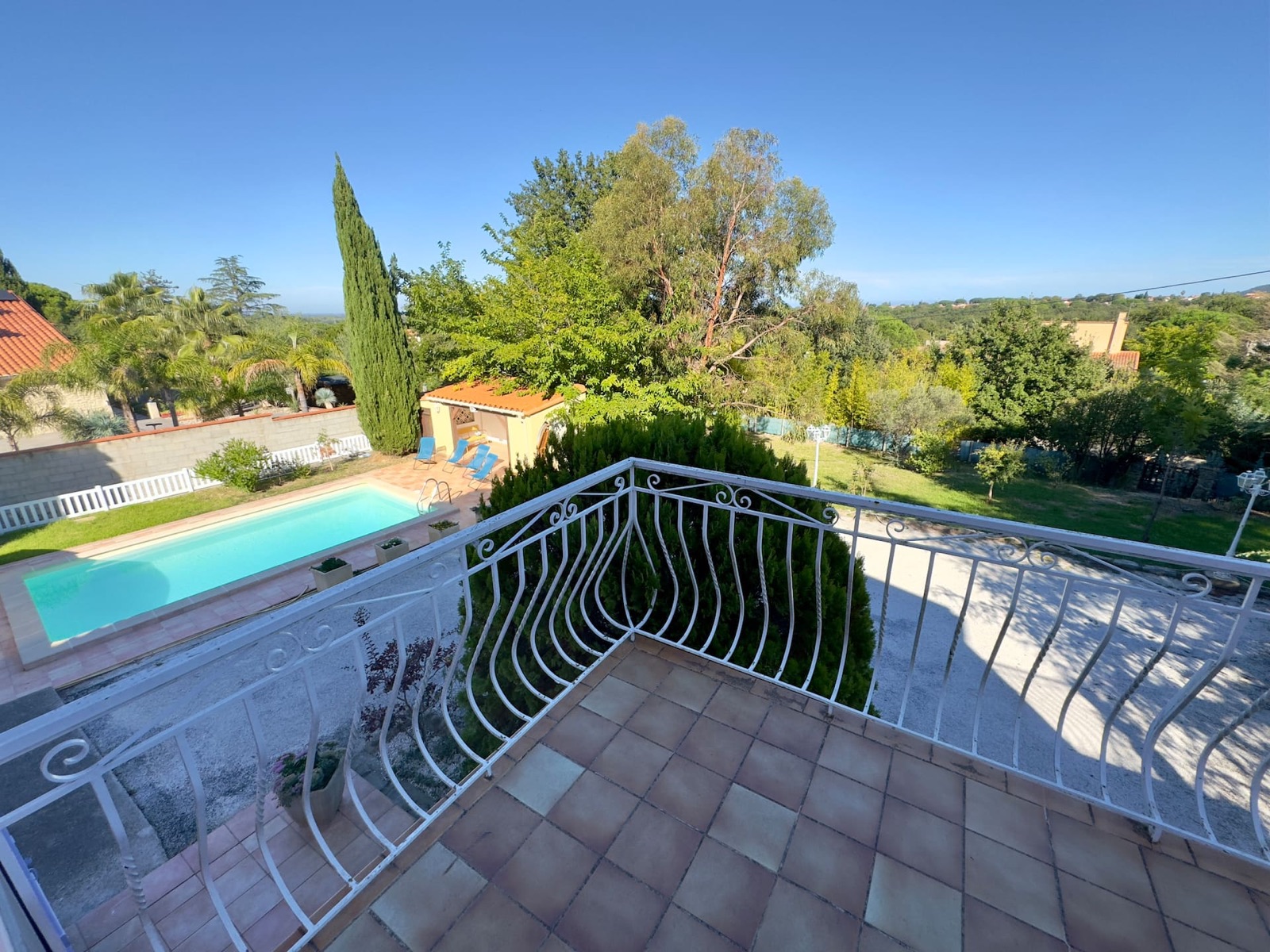 Vue du balcon sur la piscine et le jardin